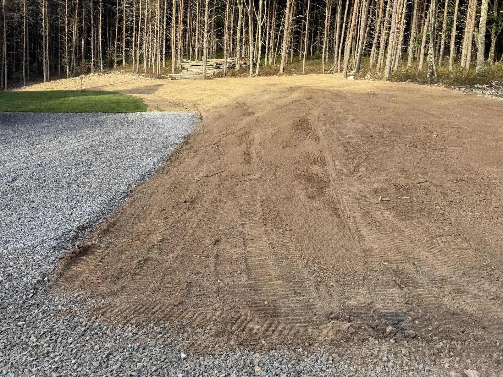 Topsoil spread and raked over a graded pad, fresh gravel along its edge